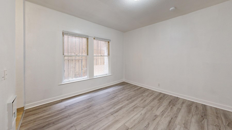 A room with wooden flooring and a window with blinds.